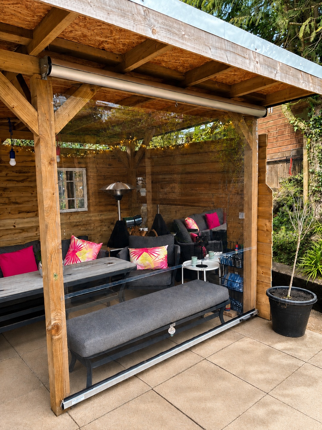 Barbara Laing's timber garden shelter with a clear roller blind across the open side