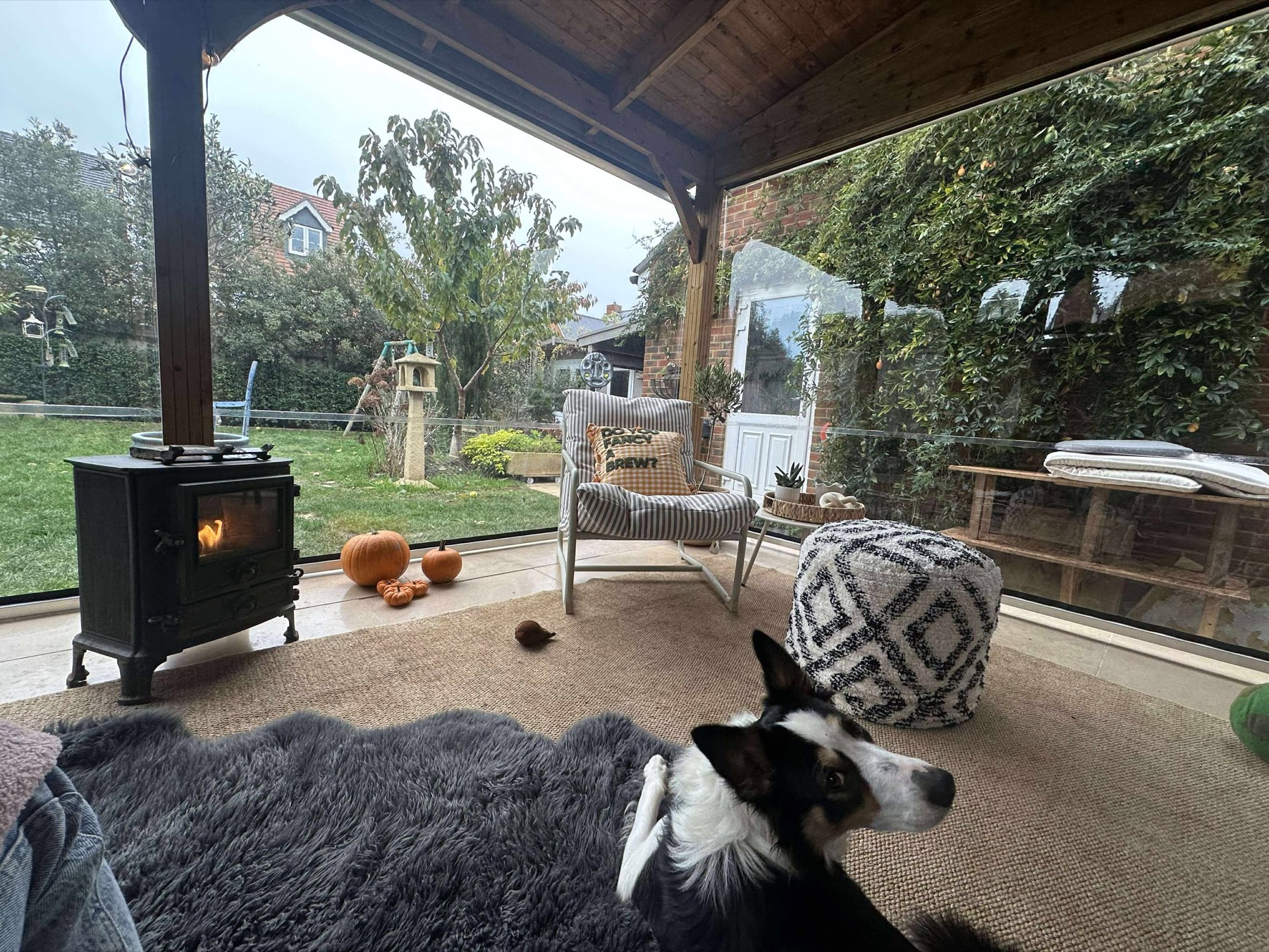 Inside Karen Mills's garden room behind the clear roller blind, wood burner lit