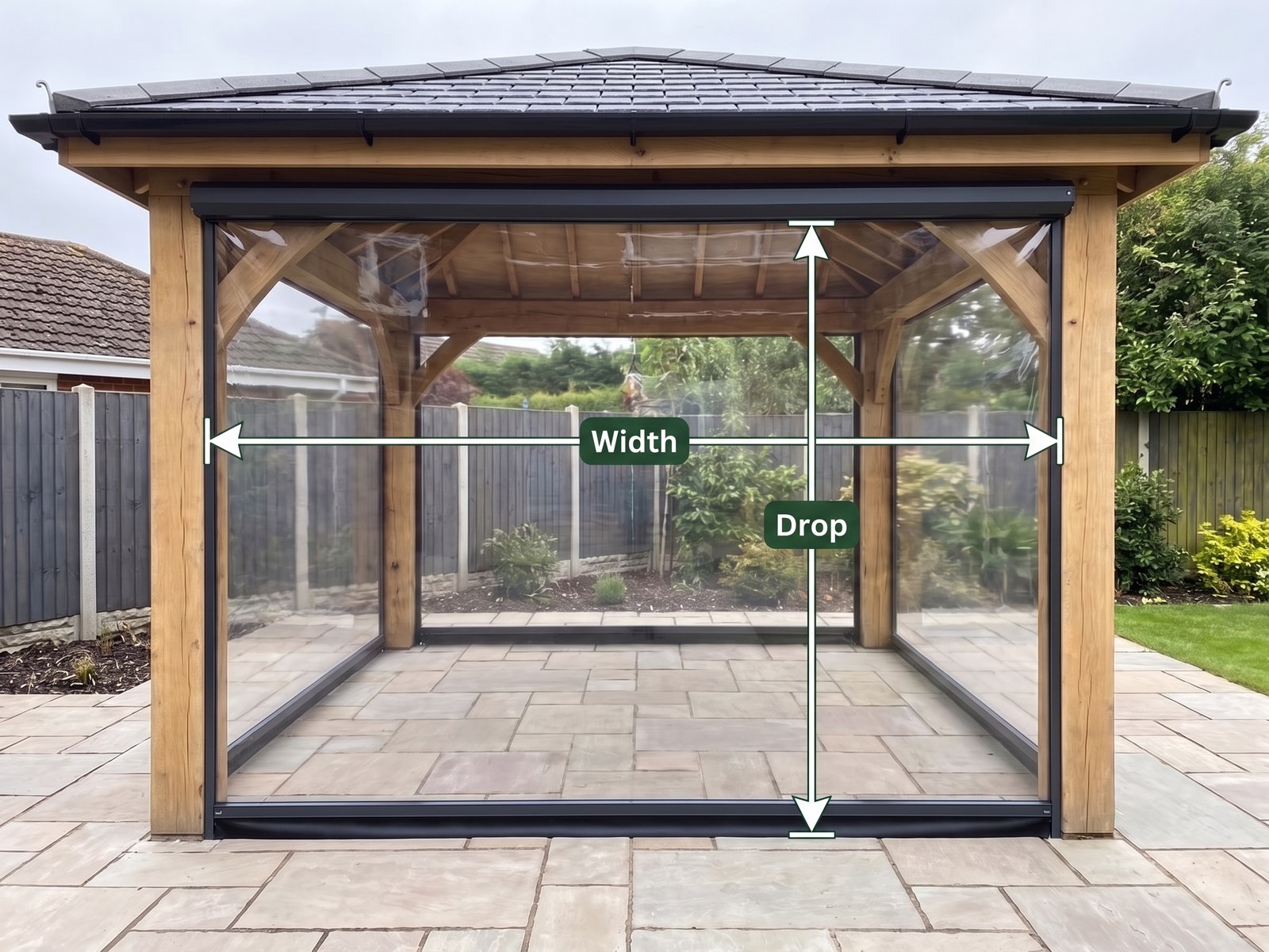 A clear PVC roller blind between two oak posts of a garden room, marked with a Width dimension from post centre to post centre and a Drop dimension from the top tube to the bottom bar