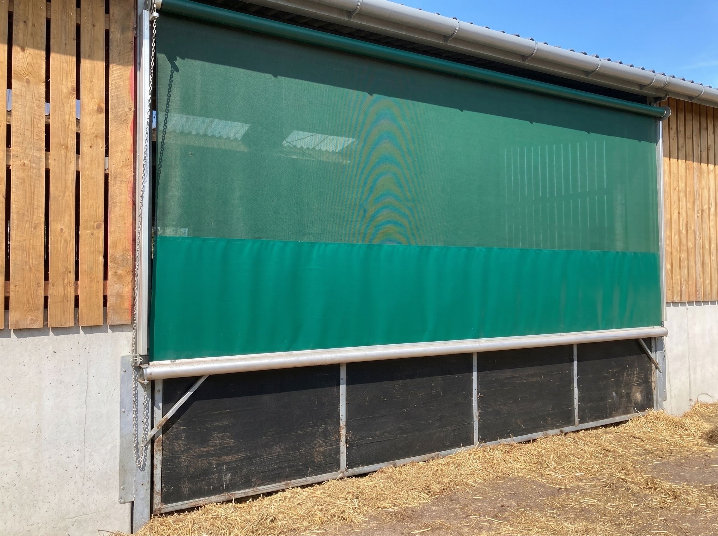 Hand chain roller blind lowered over a farm building doorway
