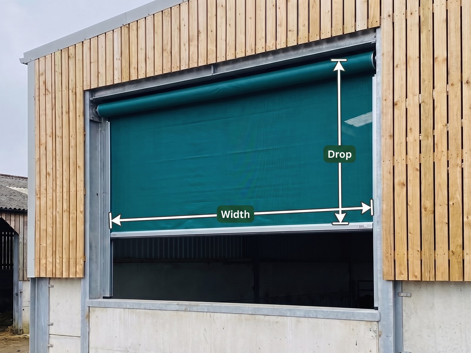 A spring loaded roller blind lowered across a livestock building opening, marked with a Width dimension across the opening and a Drop dimension from the roller tube to the bottom bar