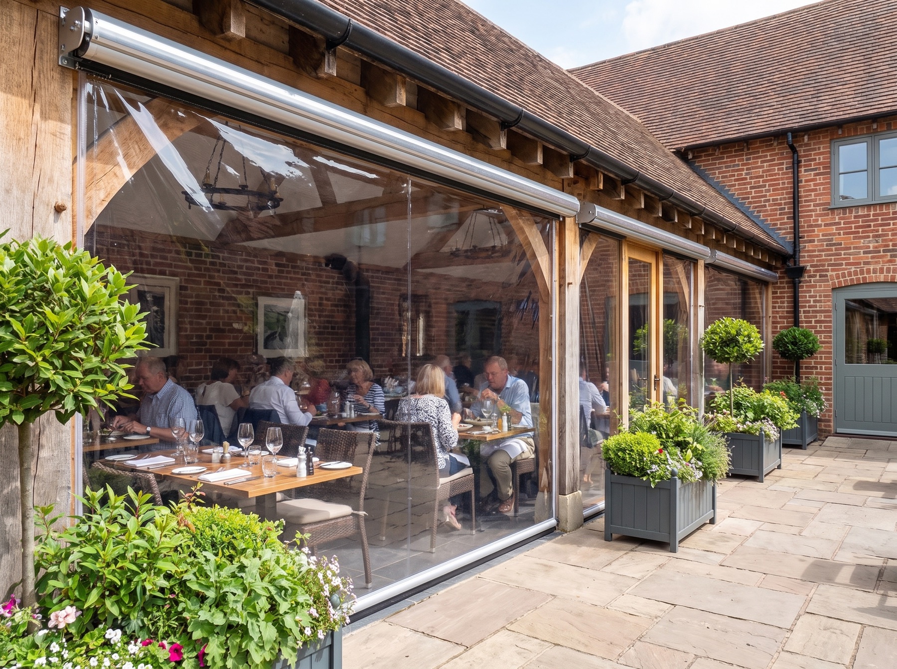Restaurant courtyard with diners behind clear roller blinds at lunchtime